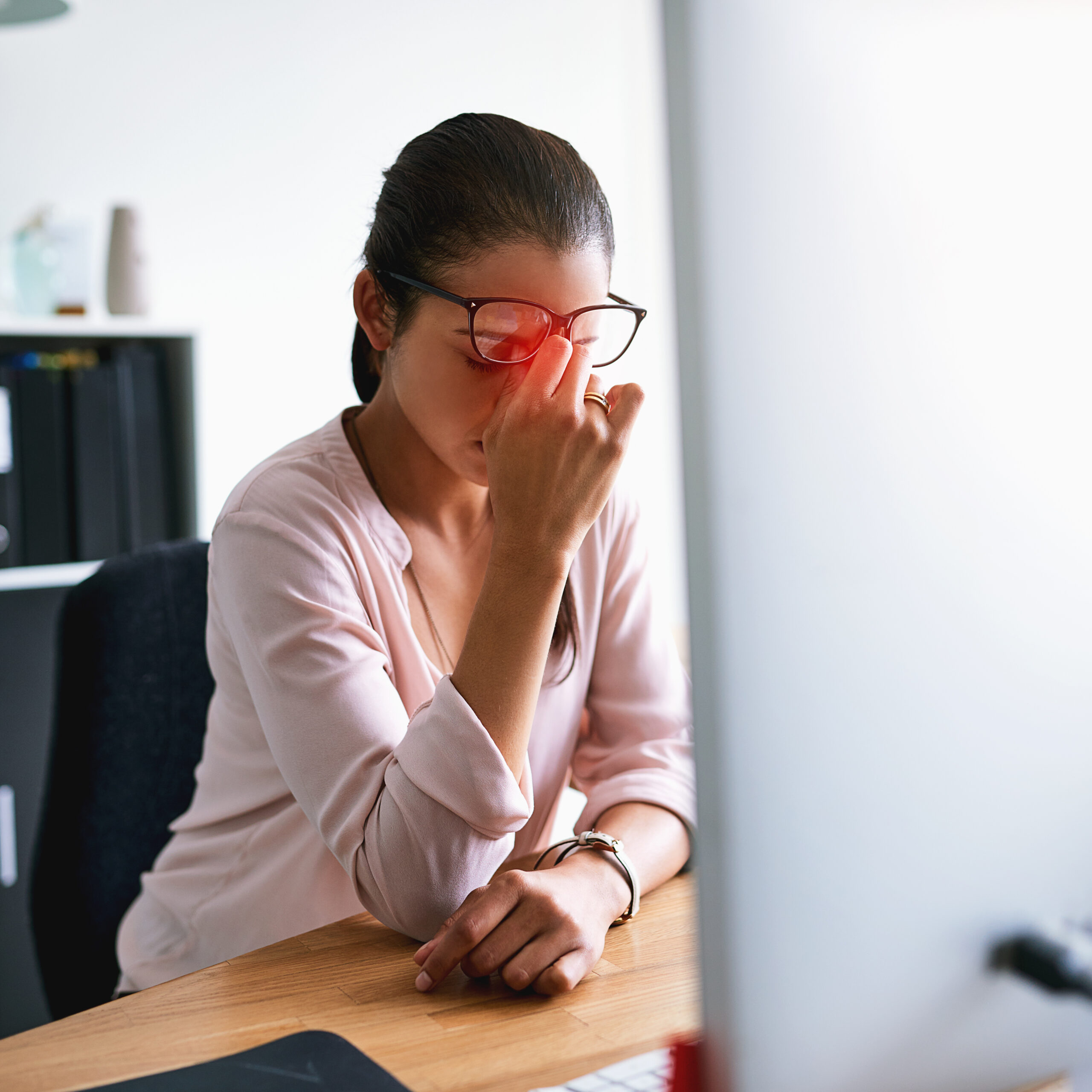 Shot of a young businesswoman suffering with a headache while working in an office